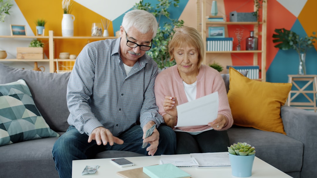 Happy family elderly man and woman are paying bills counting money then doing high-five and laughing enjoying extra cash. People and finance concept.